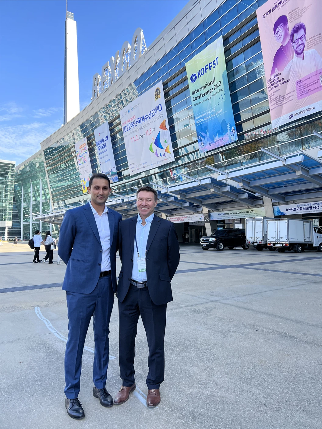 Two men in front of the Busan Exhibition and Convention Center in Korea