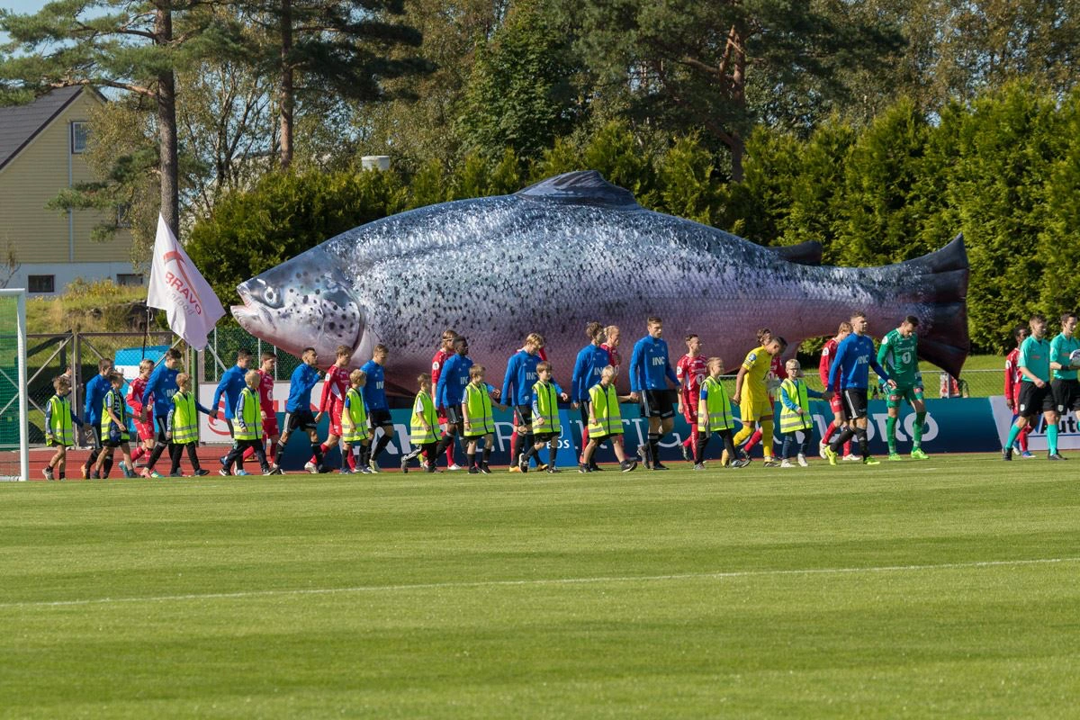 Bravo Seafood sponser Florø Fotball - bilde av A-laget med stor laks i bakgrunnen